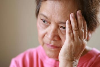 elderly asian women holding hand to head