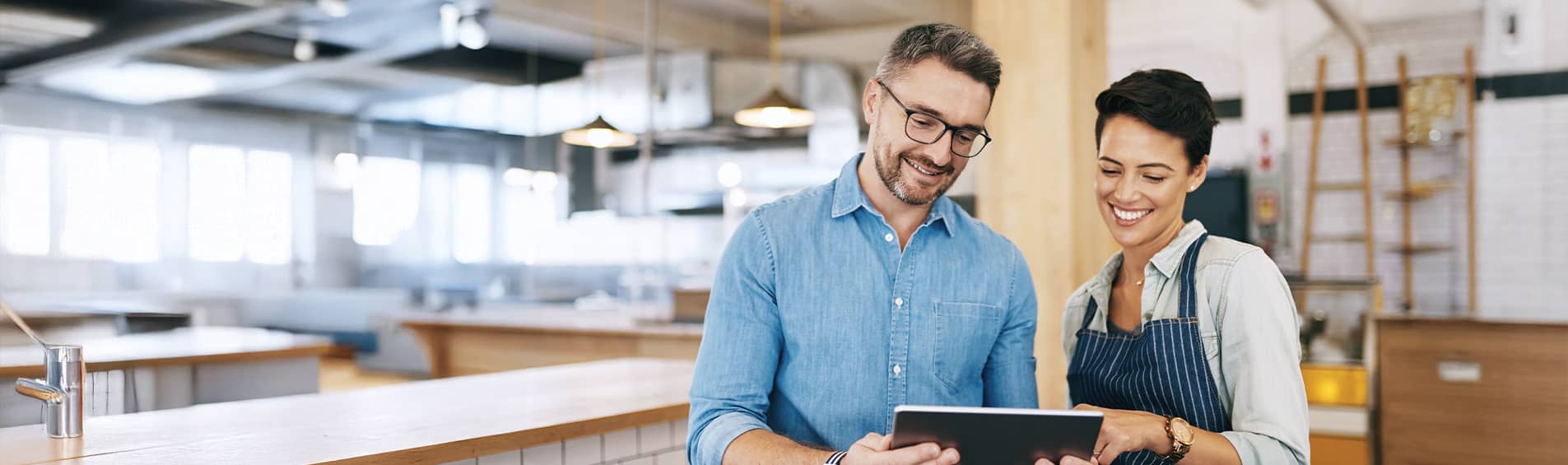 Shot of a man and woman using a digital tablet together in their coffee shop